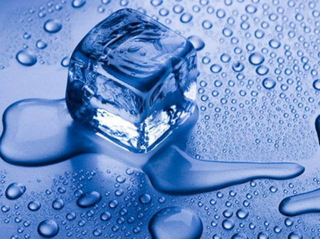 Melting ice cube with water droplets on blue surface