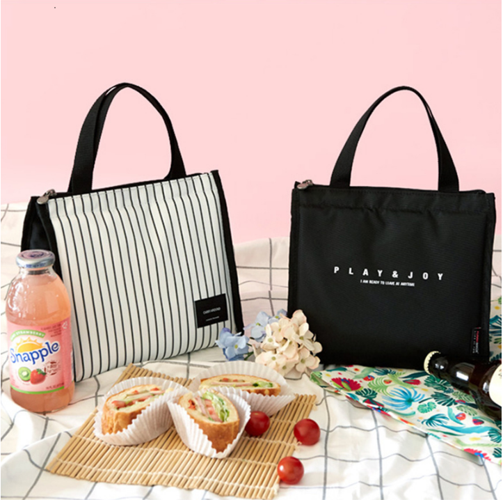 Two stylish lunch bags with food and drinks on table