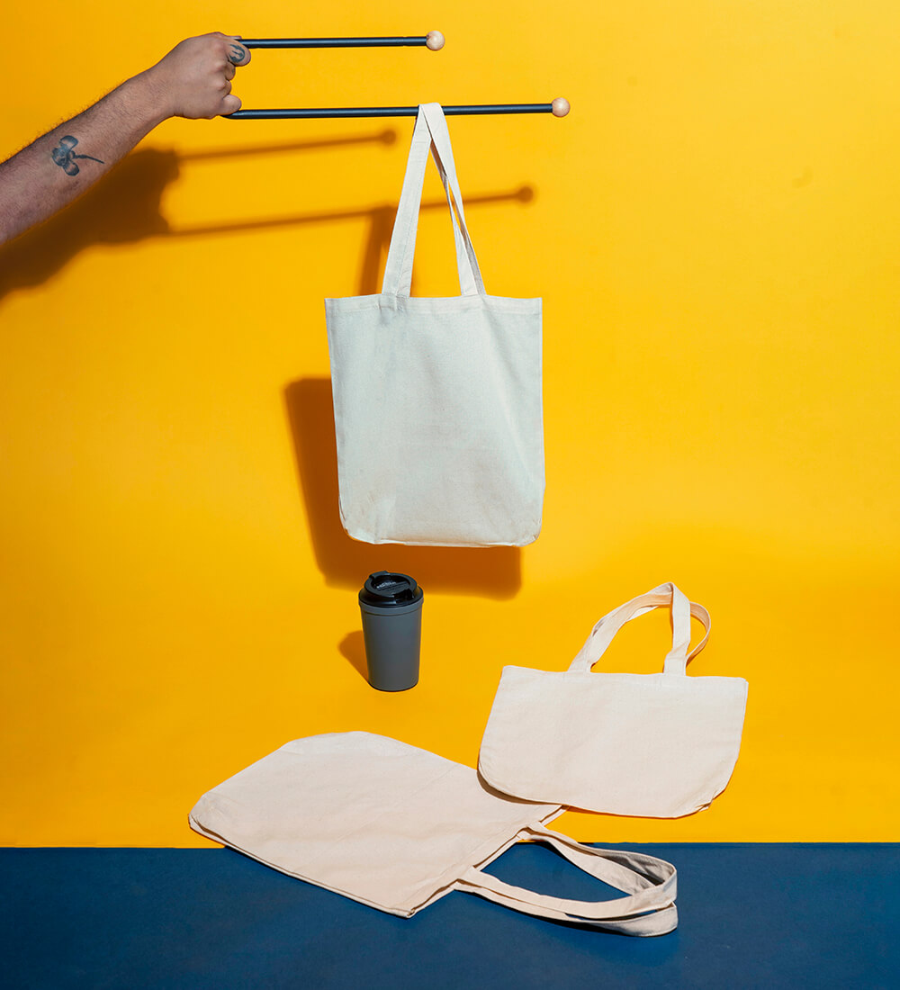 Plain cotton tote bags displayed creatively with a yellow background