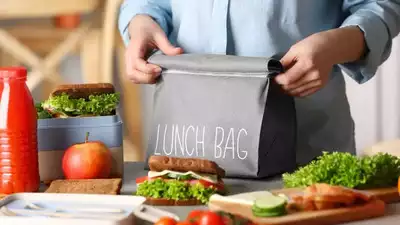 Reusable lunch bag being packed with sandwiches and fresh food items