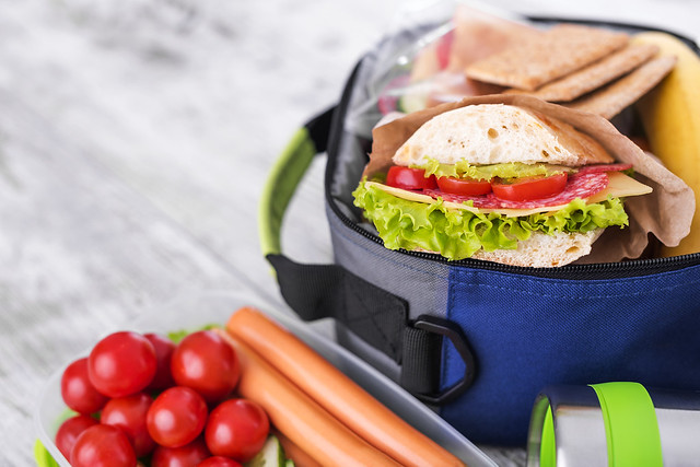 Insulated lunch bag with sandwich, fresh vegetables, and snacks