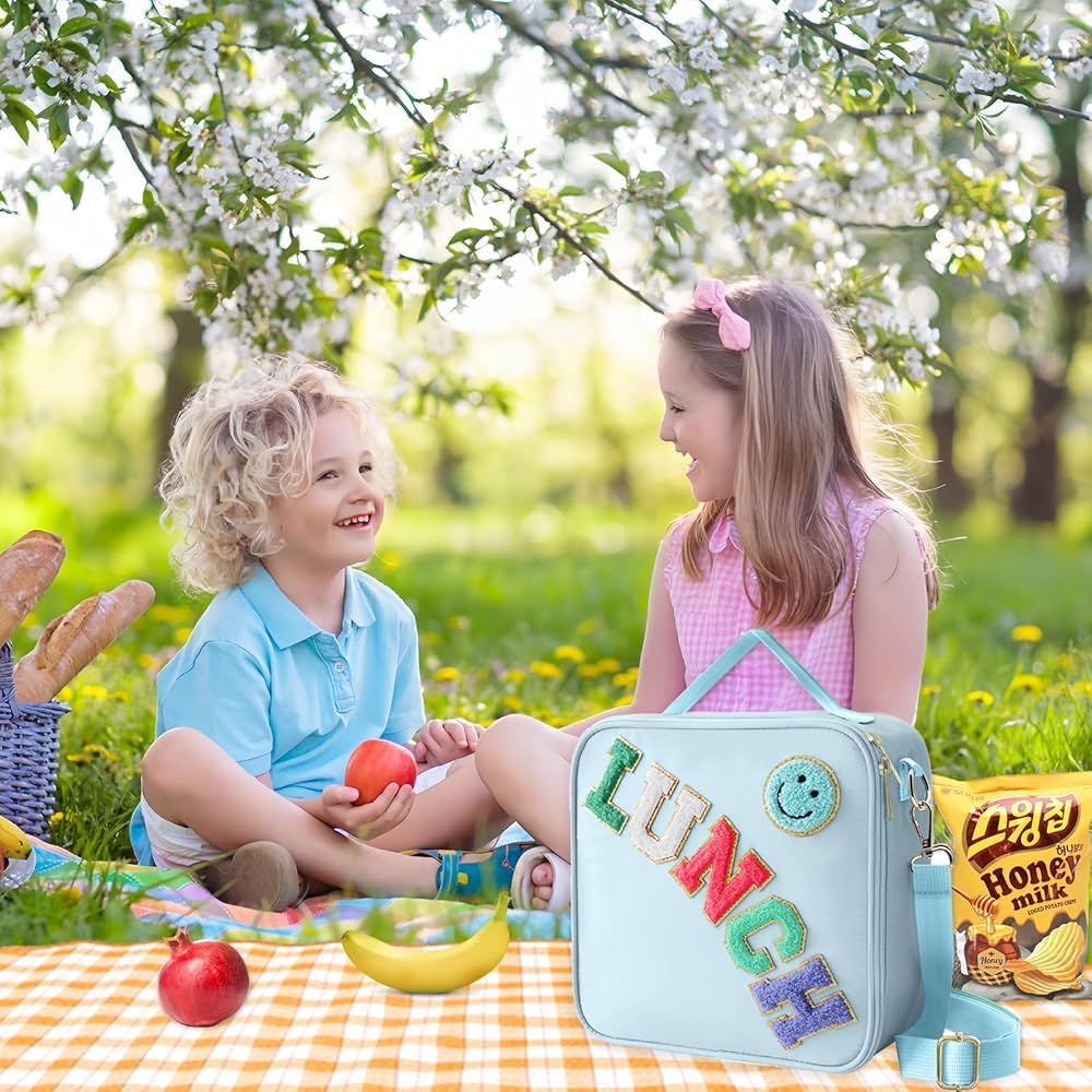 Two kids enjoying a picnic with a stylish lunch bag and snacks