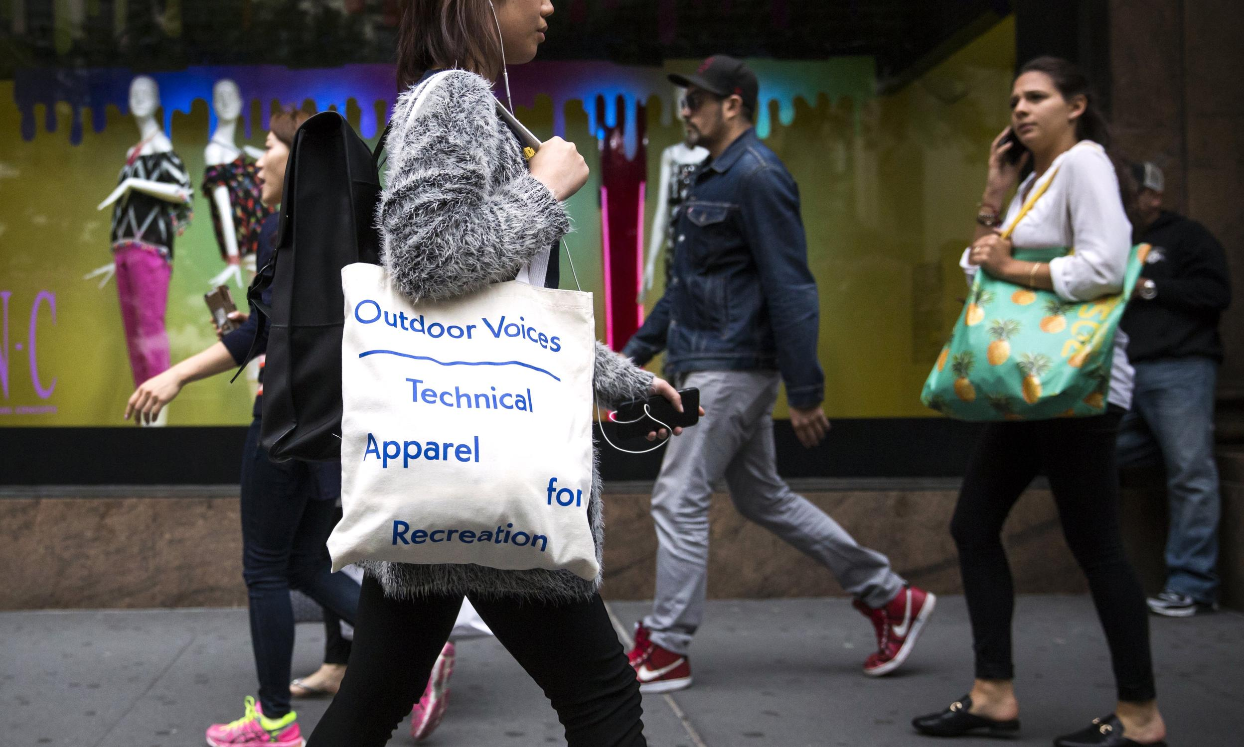 Woman walking with a custom tote bag that reads "Outdoor Voices Technical Apparel for Recreation"