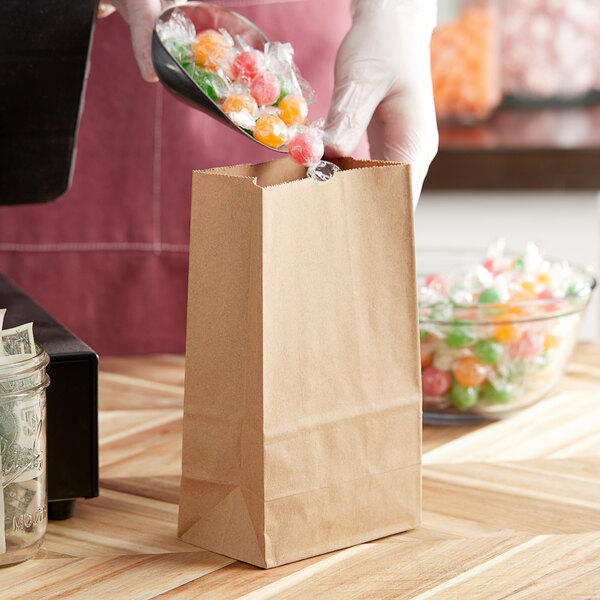 Brown paper bag being filled with colorful candies, ideal for retail use