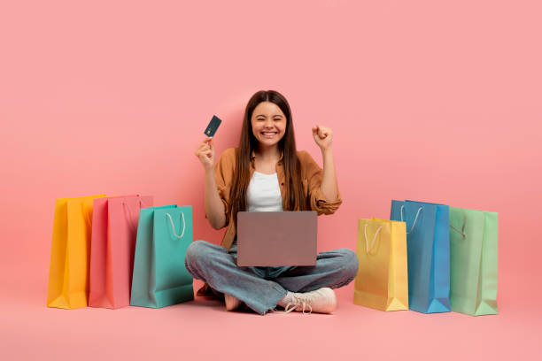 Happy woman shopping online with colorful paper bags around her