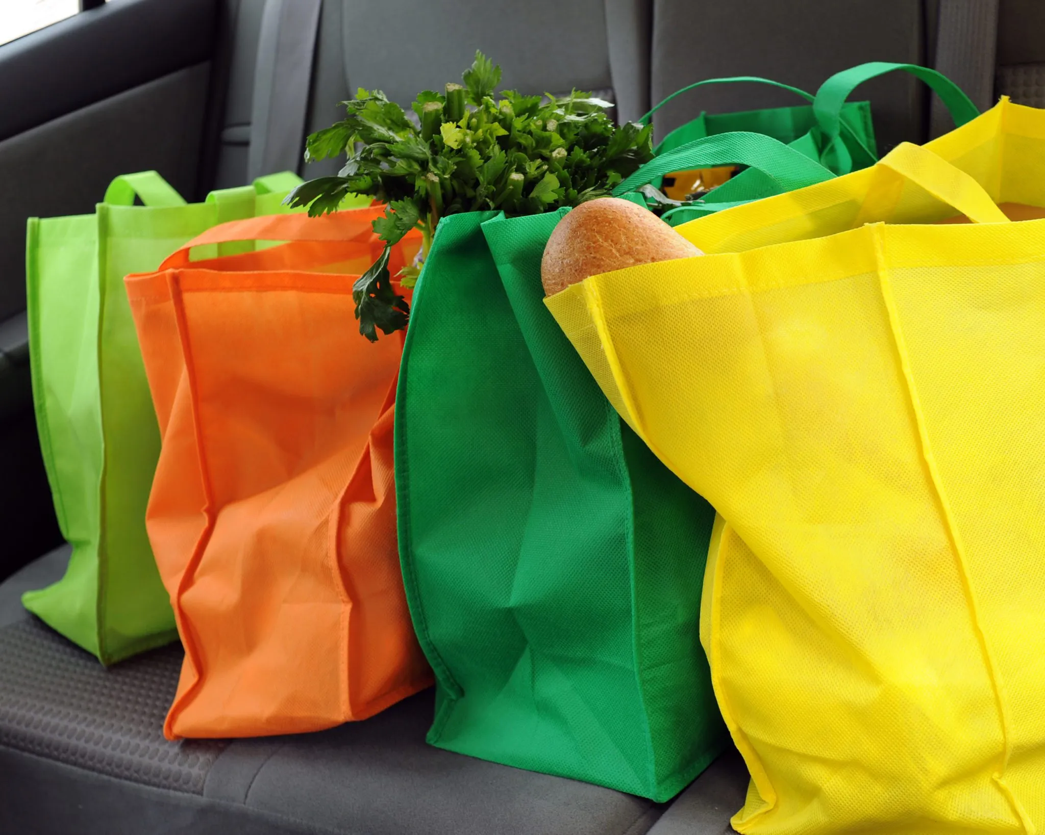 Colorful reusable non-woven shopping bags with groceries inside