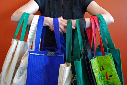 Person holding multiple colorful reusable shopping bags, eco-friendly options displayed