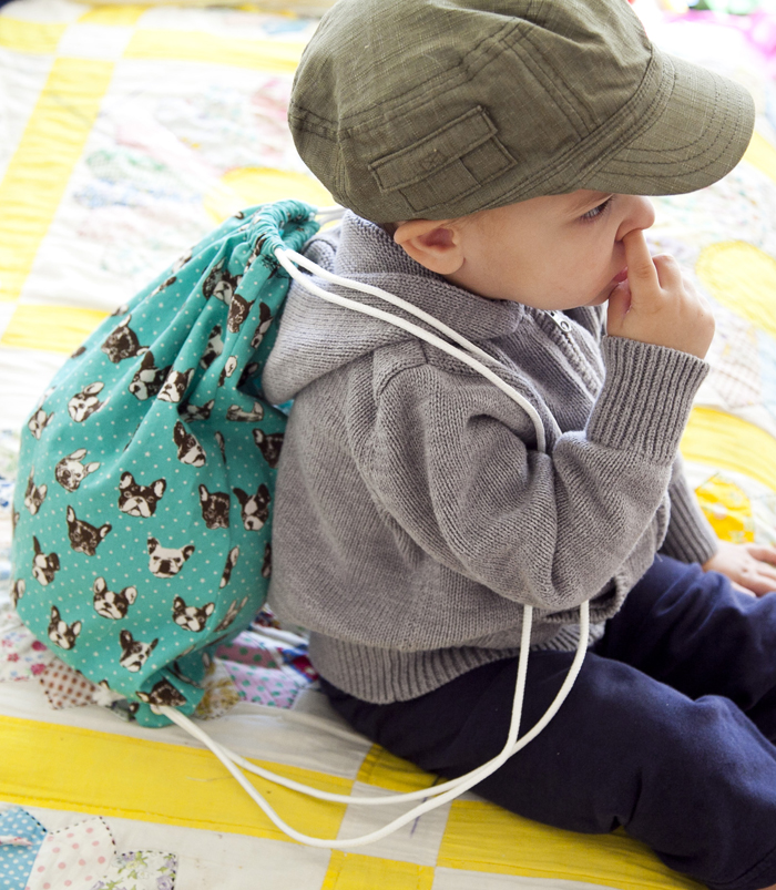 Toddler wearing a drawstring bag with a dog print design