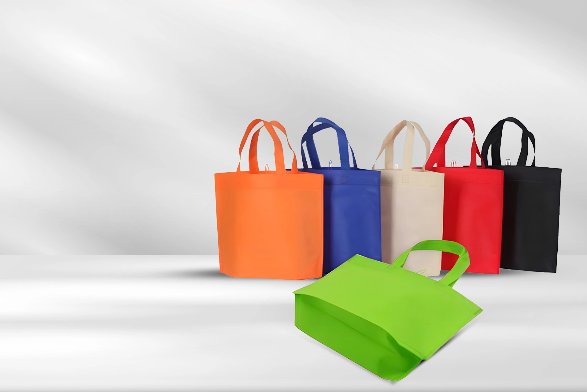 Colorful non-woven shopping bags displayed on a plain background