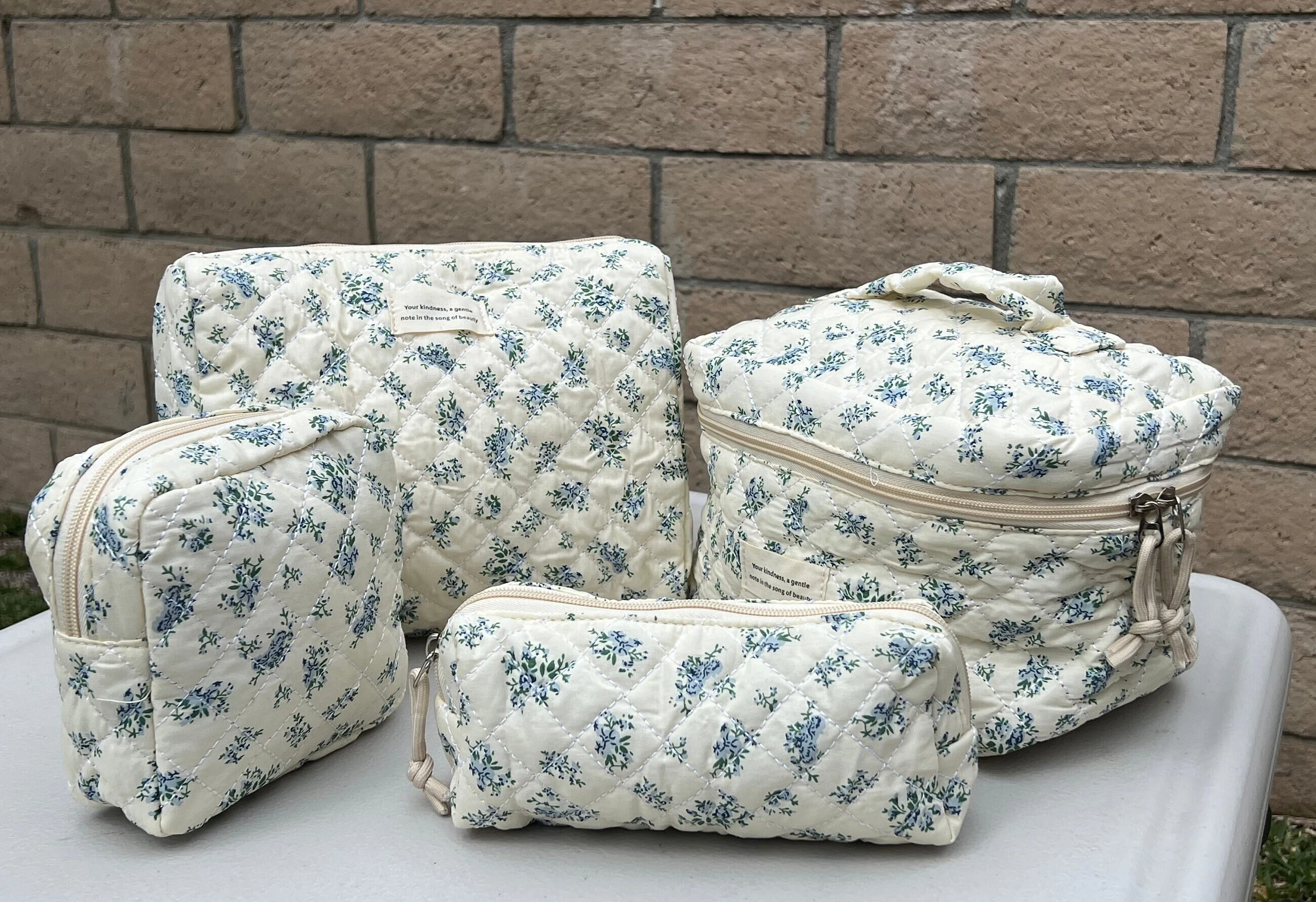 Set of quilted floral cosmetic bags in various sizes on a table