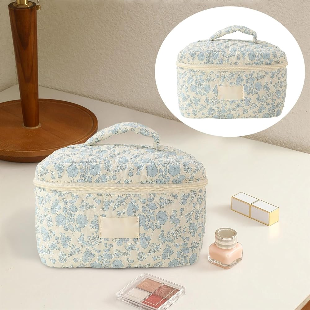 Blue floral quilted makeup bag with handle on a vanity table