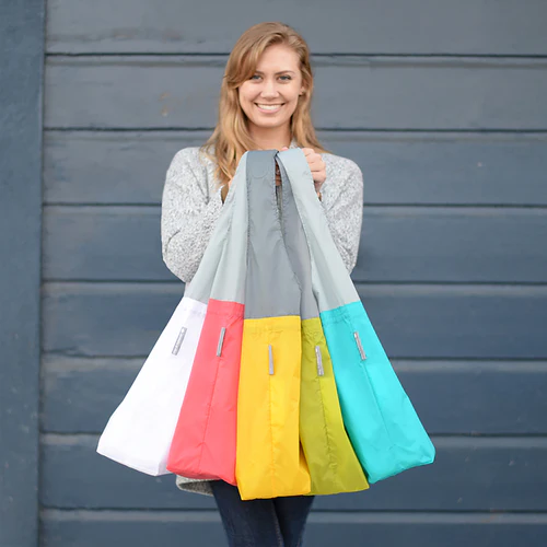 Smiling woman holding colorful reusable shopping bags