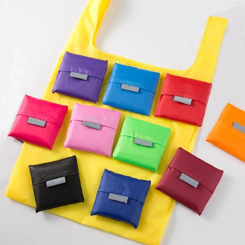 Colorful reusable foldable shopping bags displayed on a yellow bag