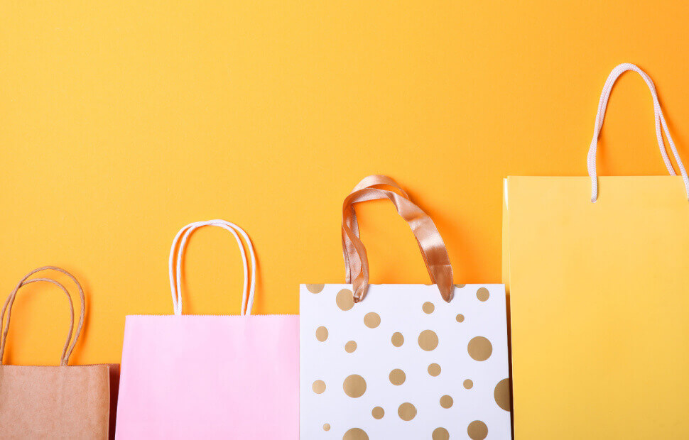 Various shopping bags against a bright orange background