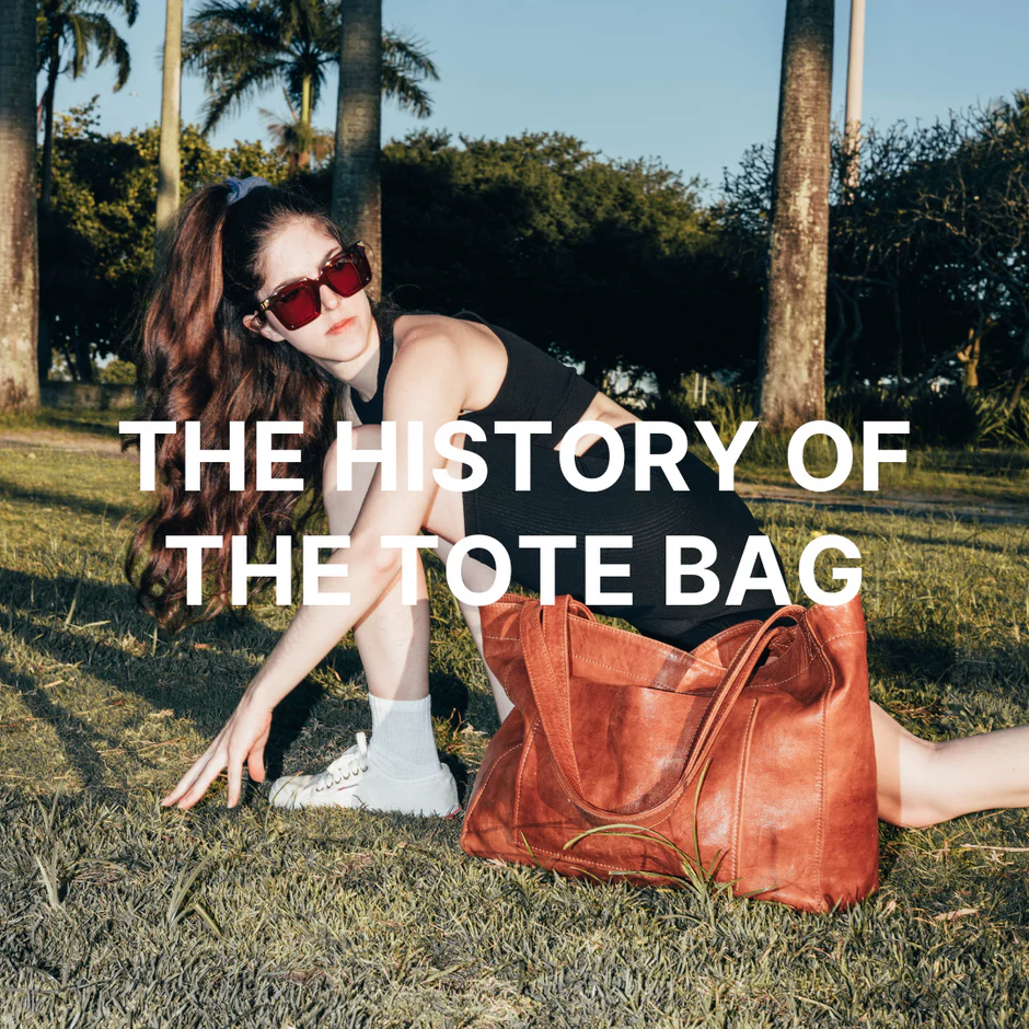 Woman sitting on grass with a leather tote bag next to her, in a sunny outdoor setting