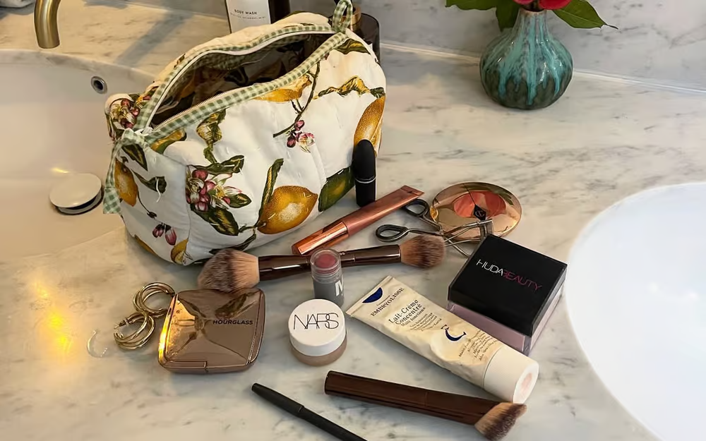 cosmetic bag with makeup items on a marble countertop