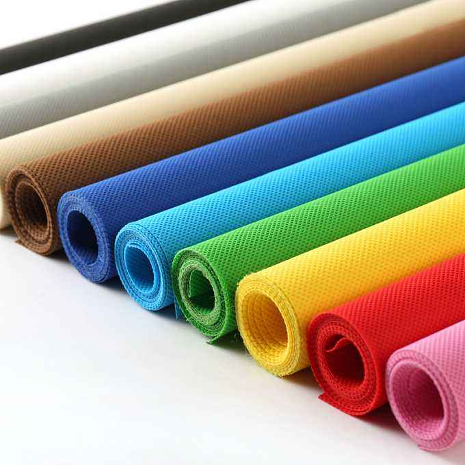 Rolls of colorful non-woven fabric in various shades, showcasing material options