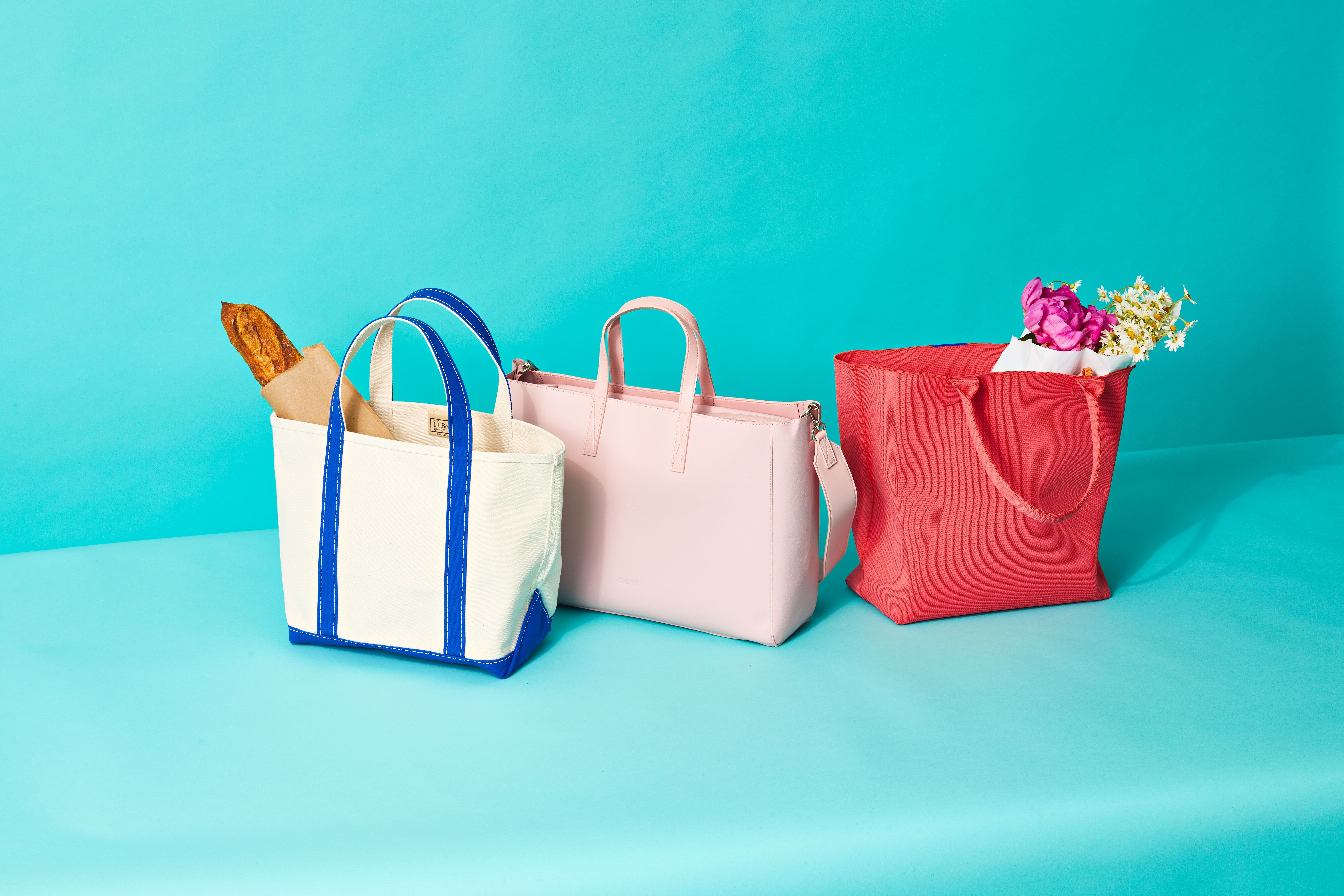 Colorful non-woven handbags in white, pink, and red with items inside