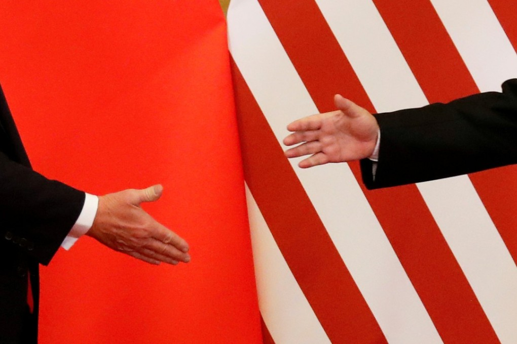 Two people reaching to shake hands in front of Chinese and American flags