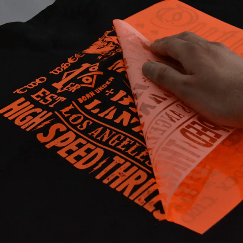Peeling off heat transfer vinyl from black t-shirt design