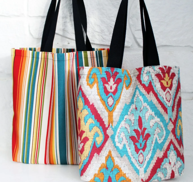 Two fabric tote bags with colorful patterns and black handles