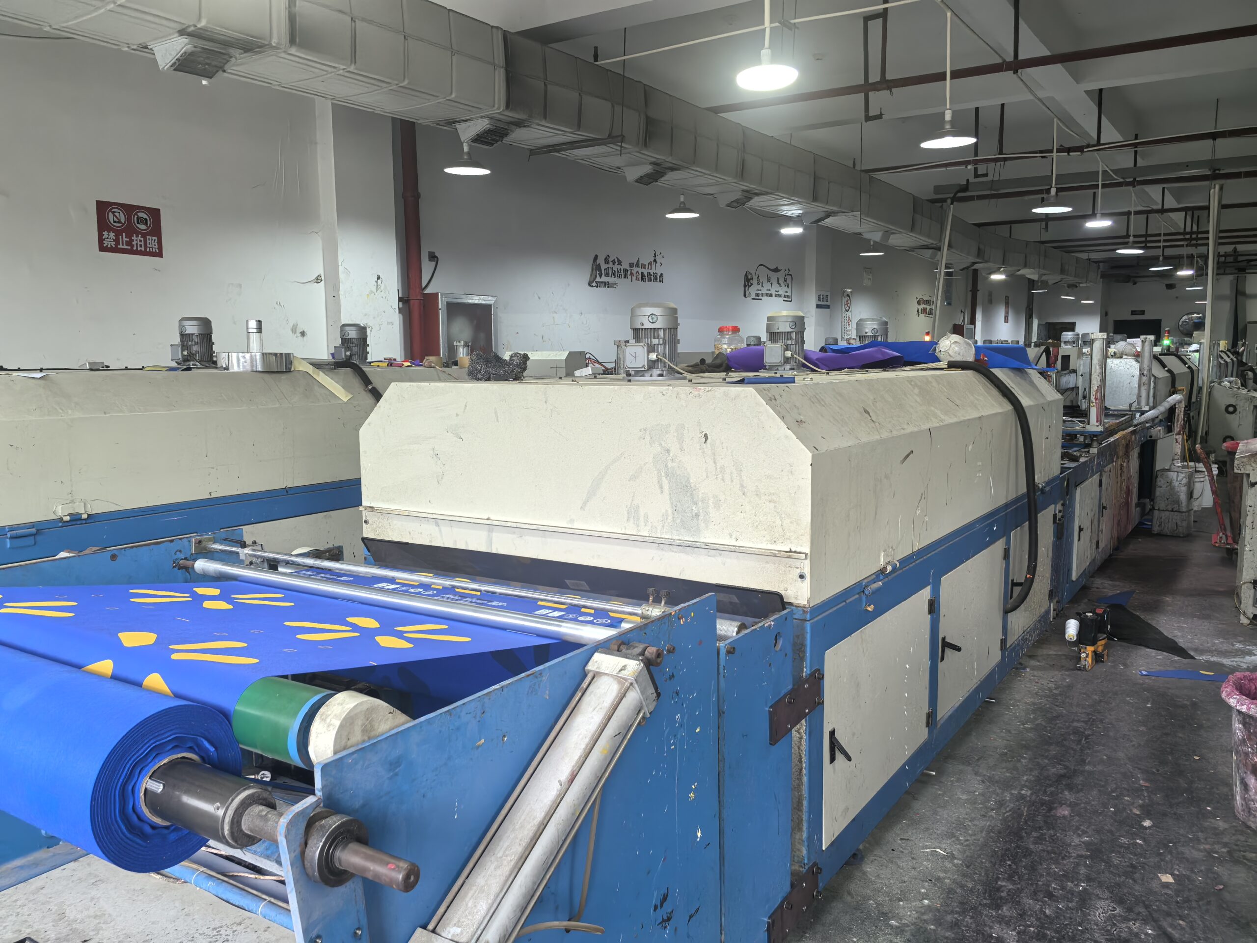 Non-woven bag production line with blue fabric and yellow logo