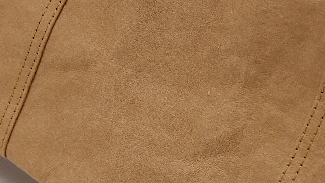 Close-up of brown non-woven fabric material with stitching