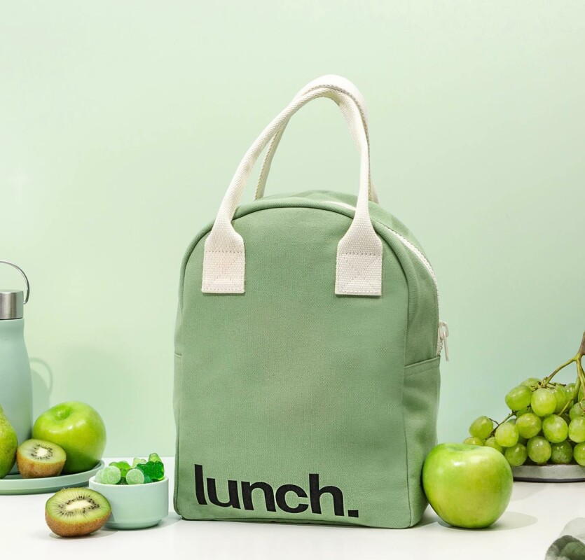 green lunch cooler bag with white handles surrounded by green fruits