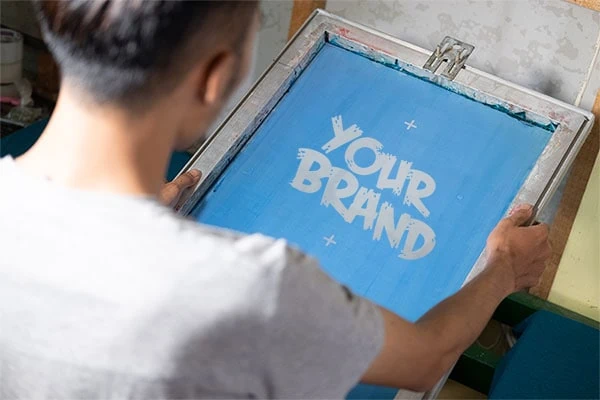 Worker preparing custom logo printing screen for bags