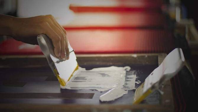 Worker screen printing custom logo with white ink