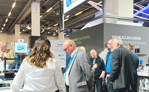 Visitors entering international trade show with staff assisting at gates