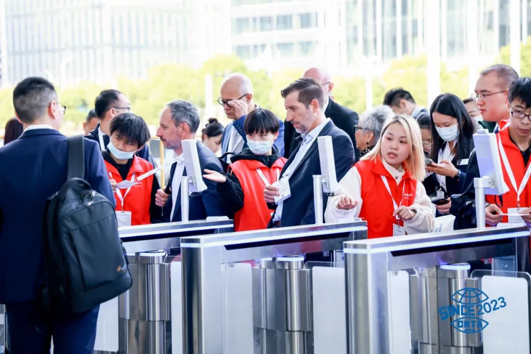 Visitors entering international trade show with staff assisting at gates