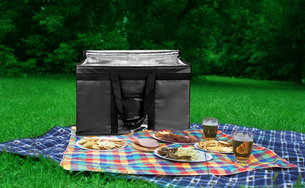 Large black insulated cooler bag on picnic blanket with food and drinks
