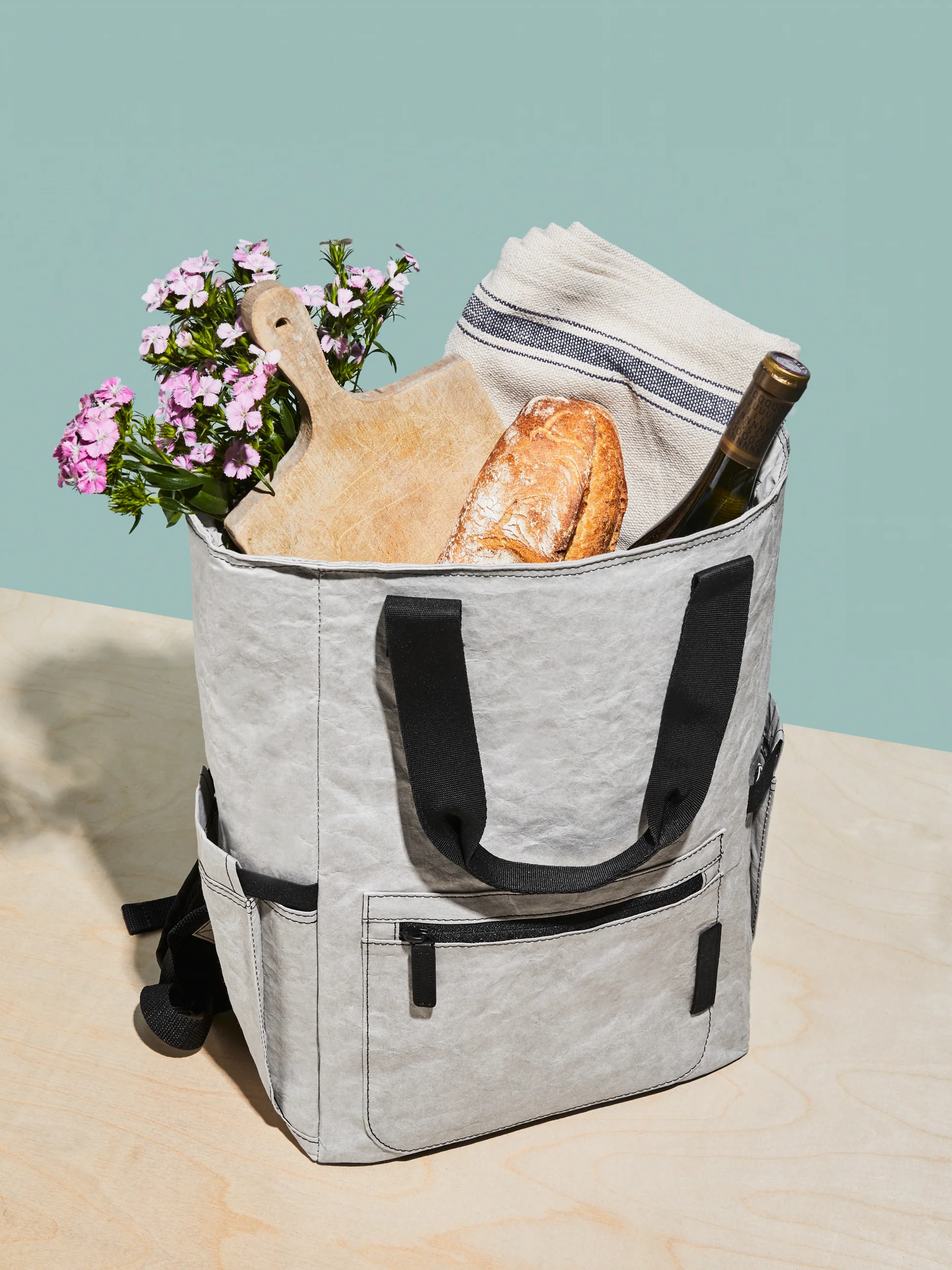 grey aluminum foil insulation backpack with bread, wine and flowers