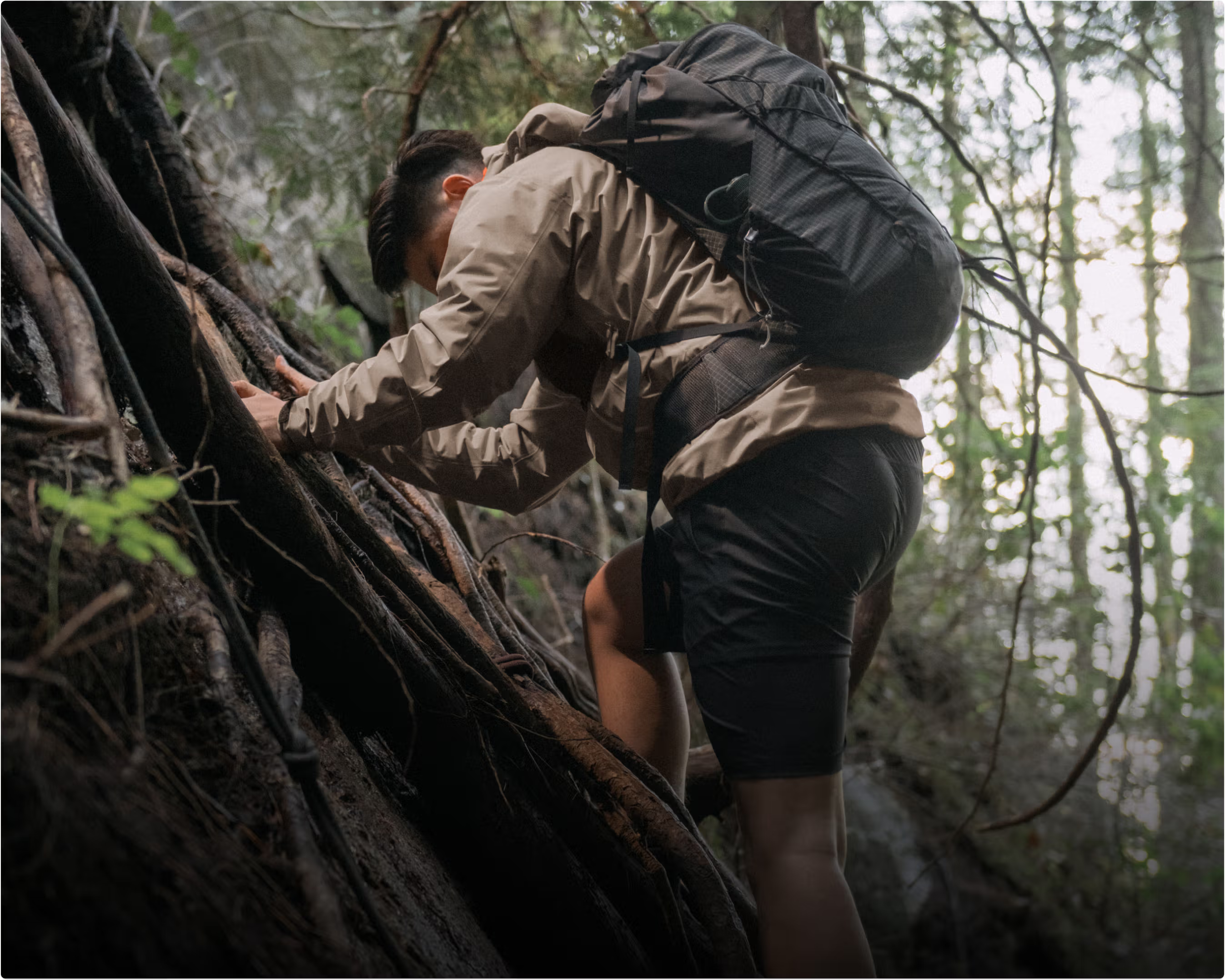 Man hiking uphill with a large backpack in dense forest