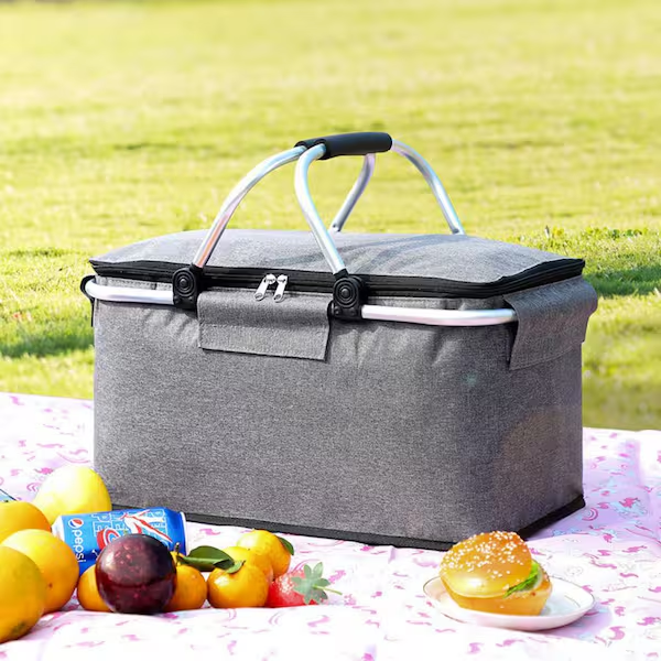 Gray insulated picnic basket on blanket with food and drinks