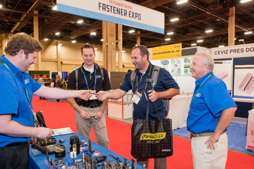 Visitors entering international trade show with staff assisting at gates