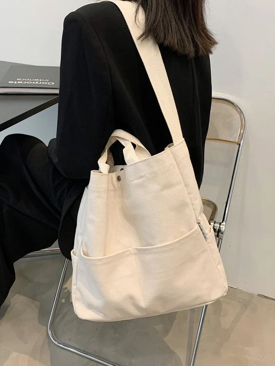 Minimalist off-white canvas tote bag with multiple exterior pockets