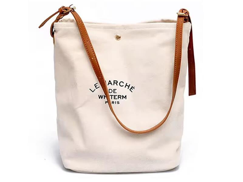 White canvas bucket bag with adjustable brown leather shoulder strap