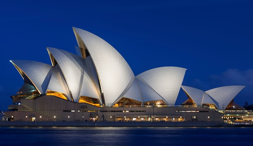 Sydney Opera House illuminated at night against deep blue sky