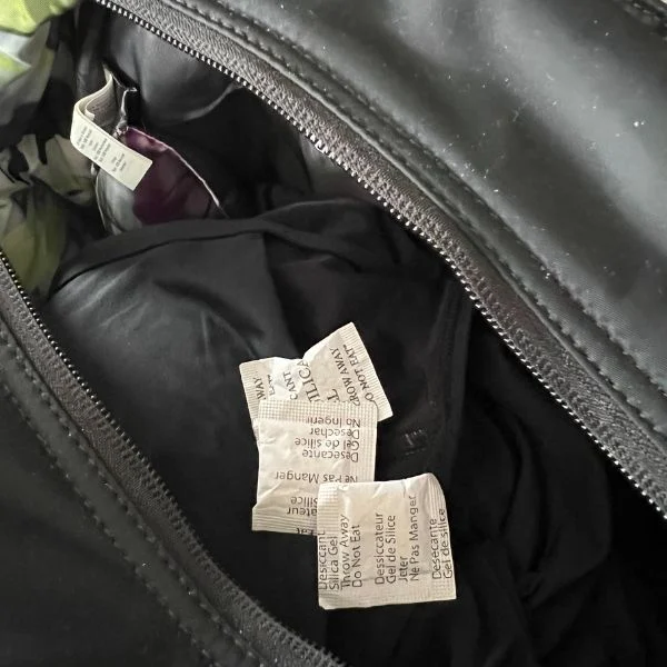 Close-up of clothing care labels inside a black zippered bag