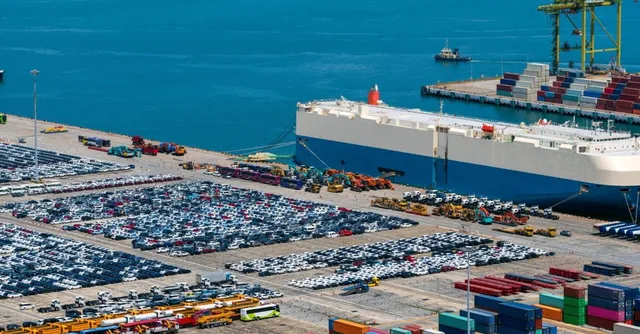 Large cargo ship docked at port with cars and containers